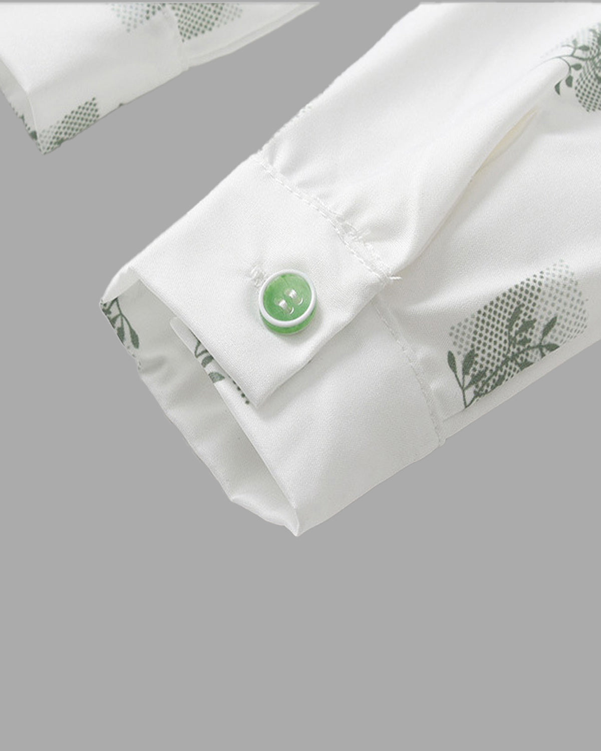 Close-up detail of the premium woven cotton shirt showing subtle botanical prints and matching green button on the sleeve cuff