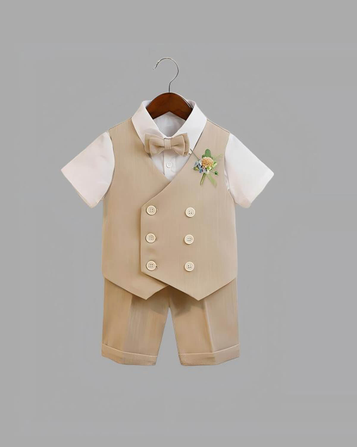 Hanger display of the complete 4-piece boys summer formal set, including a beige vest, matching shorts, a white short-sleeve shirt, and a bow tie.