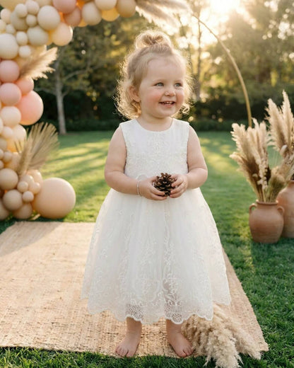 Toddler girl smiling in Pearl Ivory Embroidered Lace & Tulle Party Dress at an outdoor garden wedding party with balloon arch backdrop