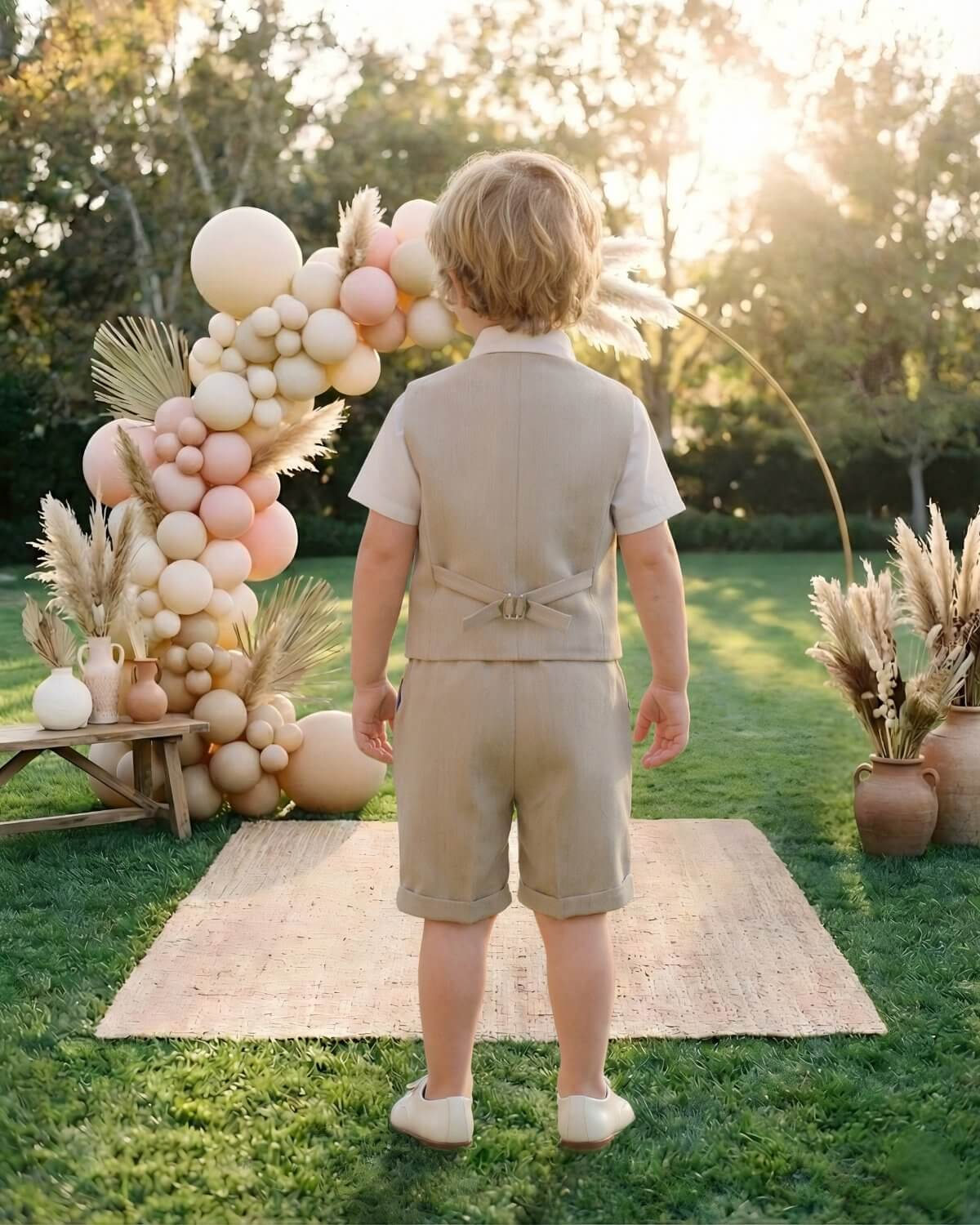 Back view of the tailored beige page boy vest and shorts, looking towards a beautiful wedding balloon arch.