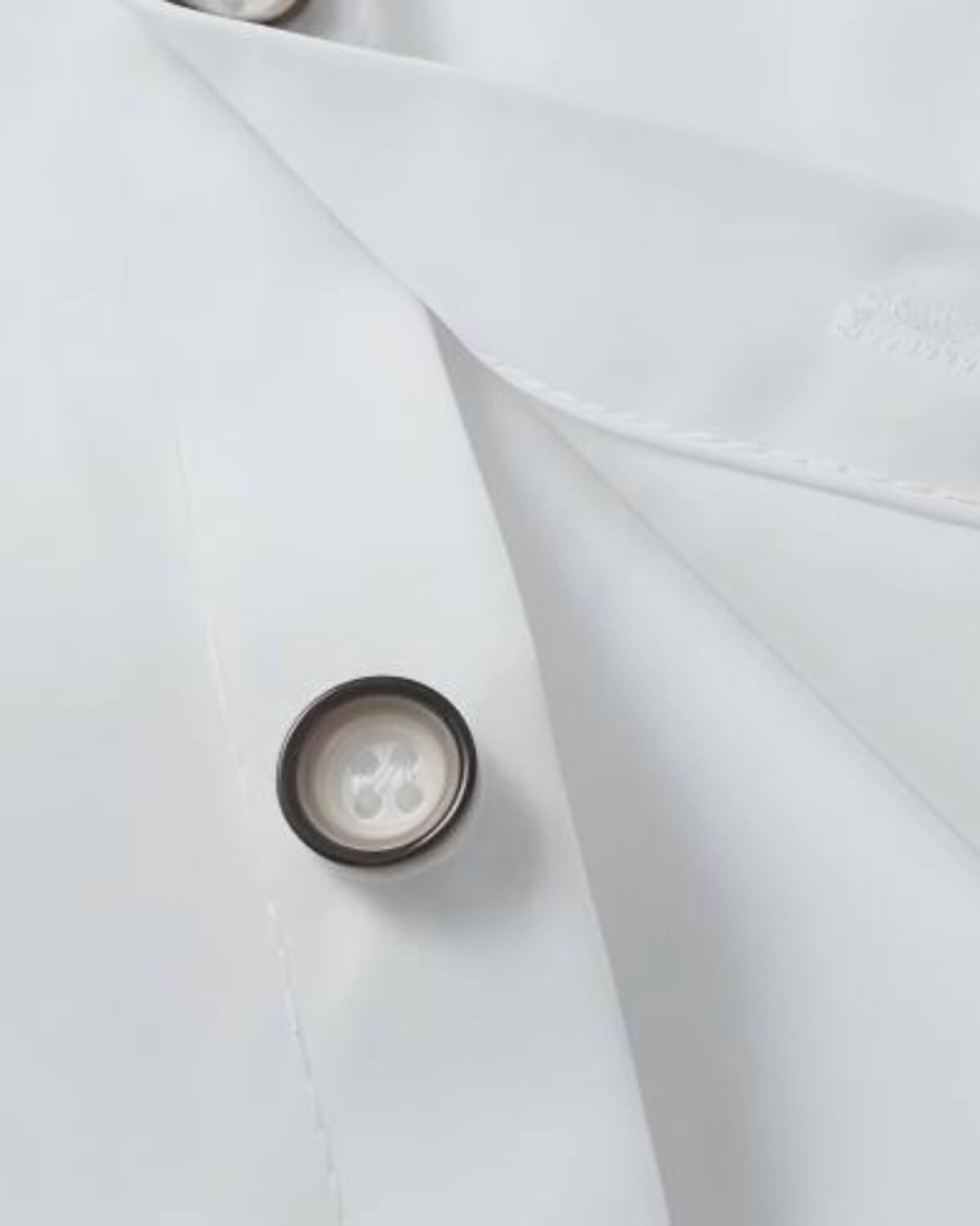 Close-up of a boys crisp white formal dress shirt showing premium stitching and a dark-rimmed button