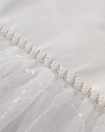 Close-up of the V-back design on an ivory white flower girl dress, featuring hand-stitched pearls and a large satin bow.