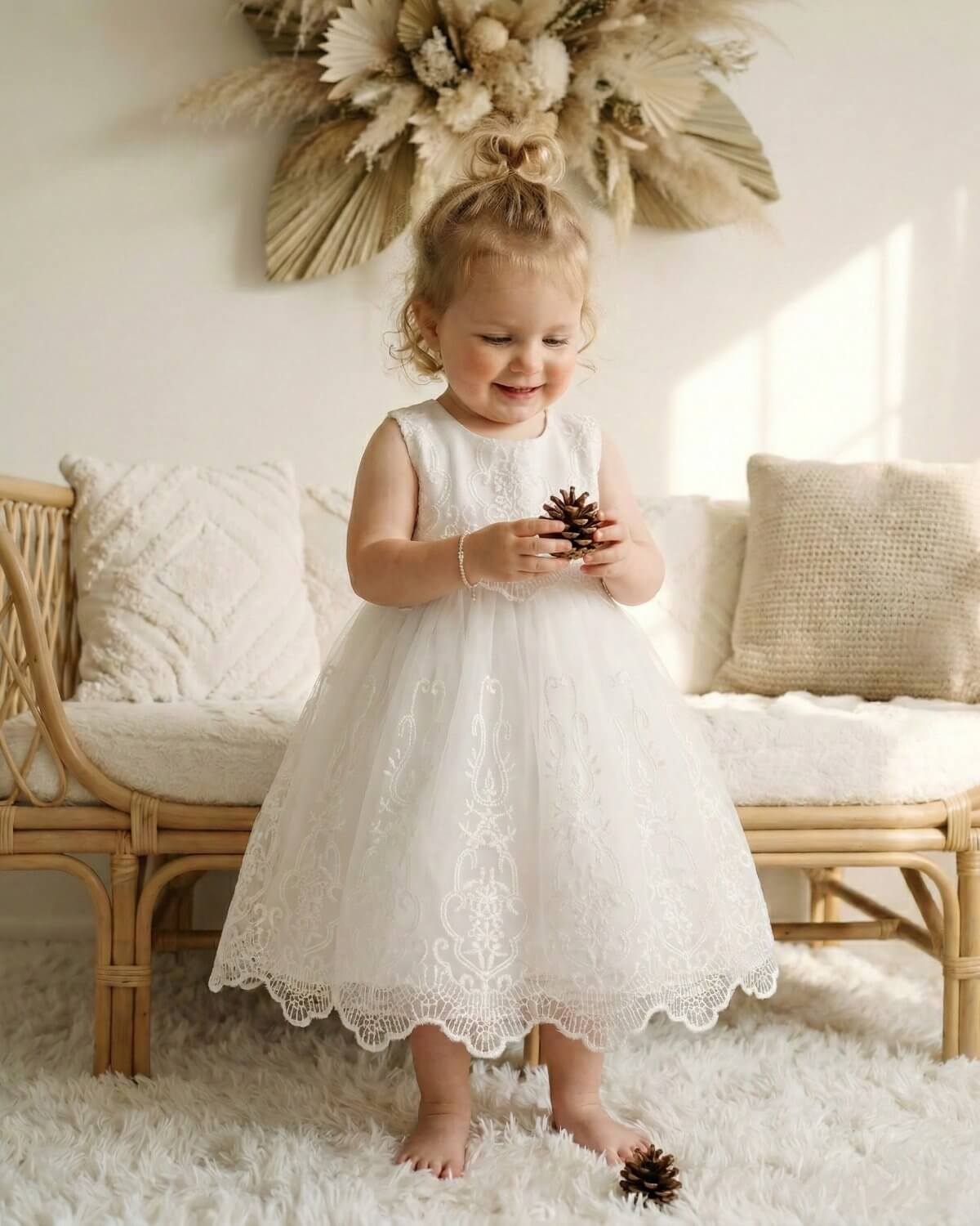 Toddler girl standing in a boho styled room wearing ivory lace tulle formal party dress for page boy weddings and holy communion