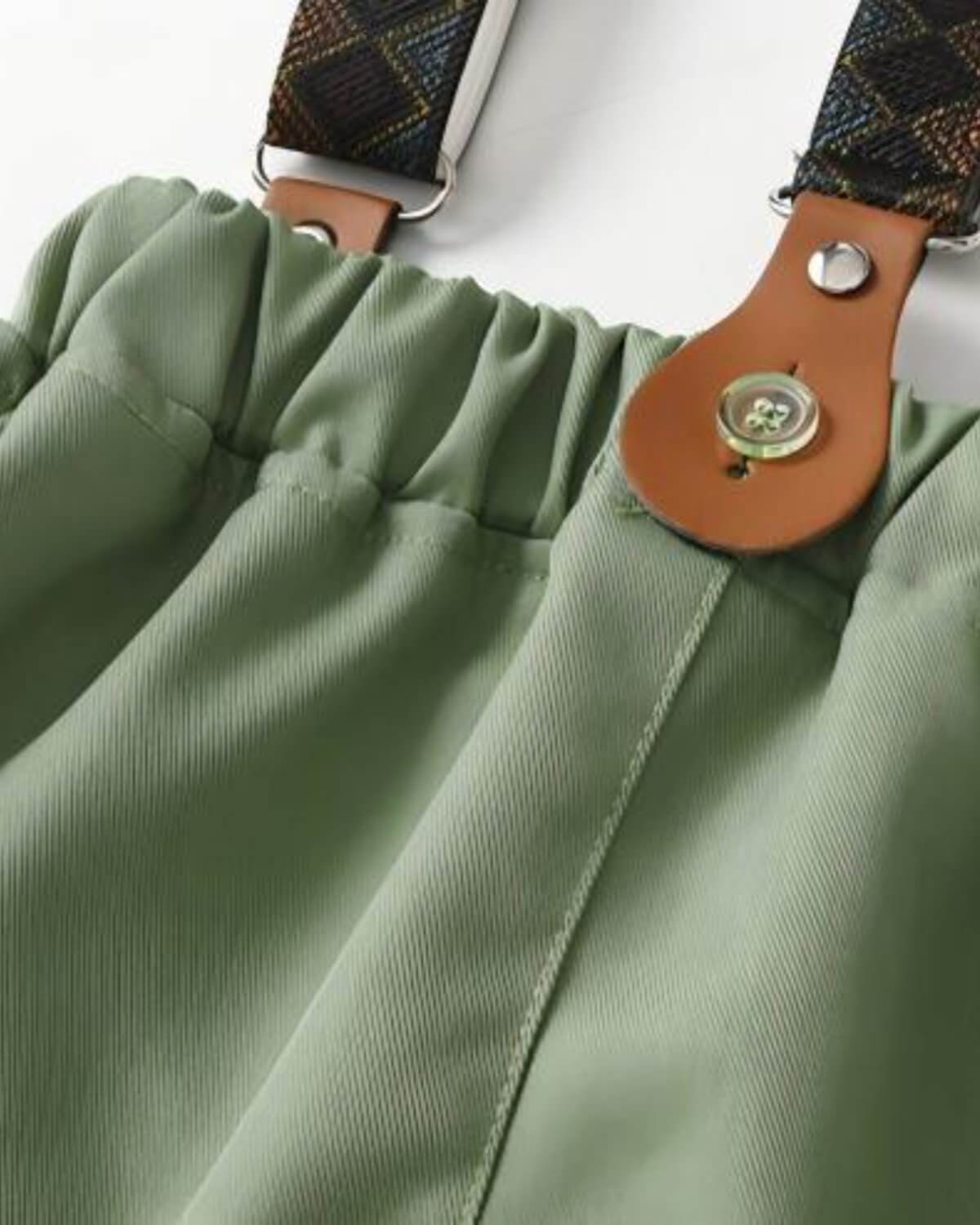 Close-up of boys sage green wedding trousers showing the comfortable elastic waistband and vintage leather suspender button attachment