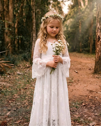 A sweet flower girl holding a white bouquet, wearing a vintage V-neck lace maxi dress with a floral crown.