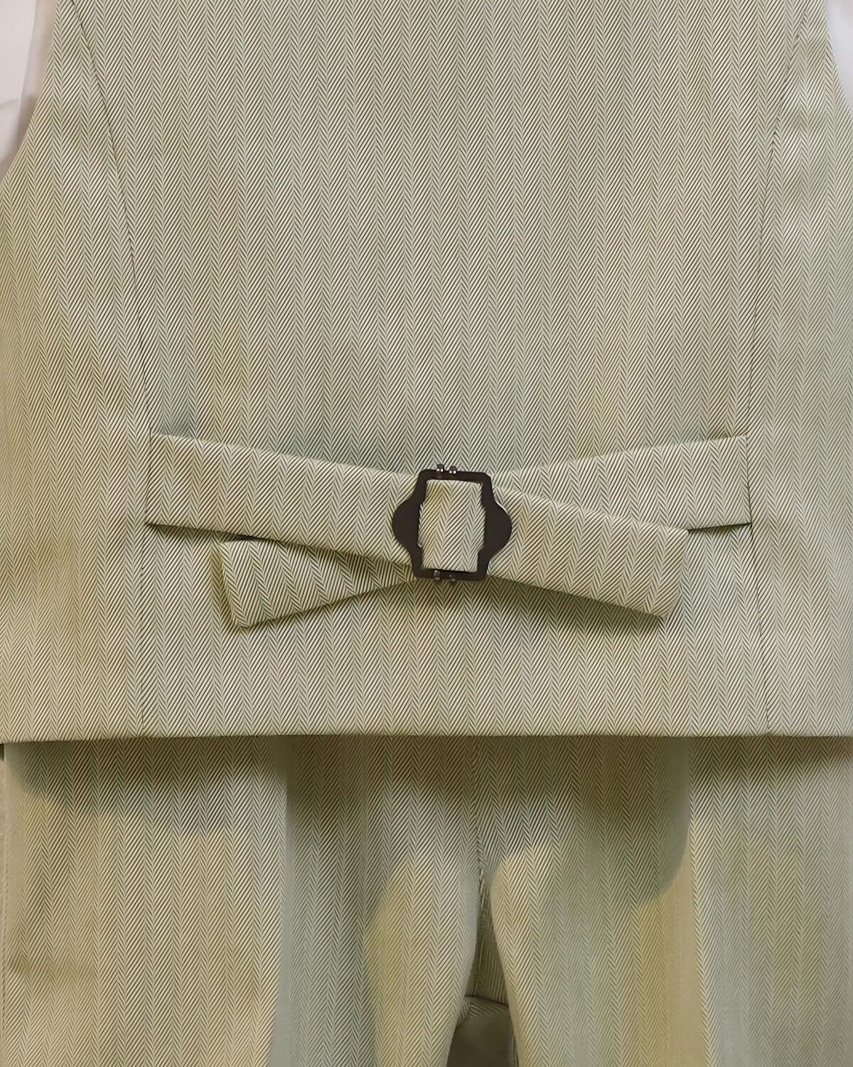 Close-up of the adjustable back strap and buckle on the boys' sage green formal vest.