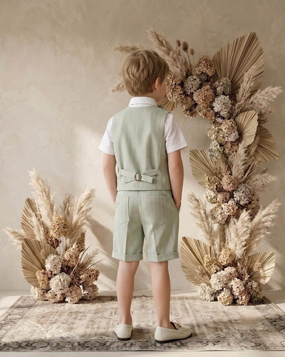 Back view of a boy wearing a tailored sage green vest and formal shorts suit set.