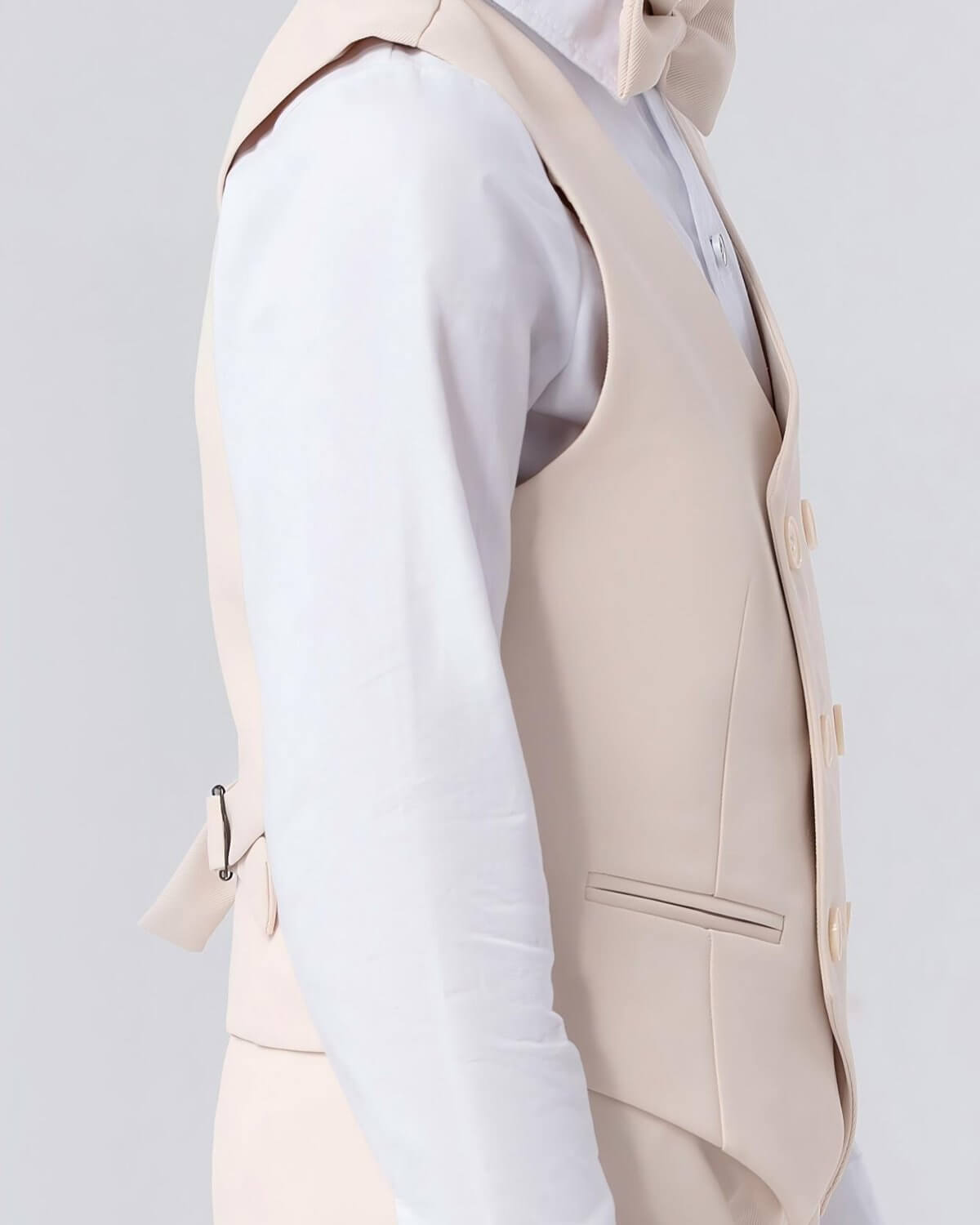 Close-up side view of a boys oatmeal double-breasted waistcoat showing the tailored fit and adjustable back cinch strap.