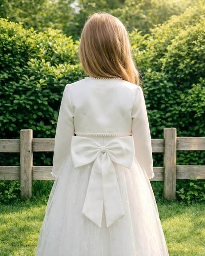Back view of a girl outdoors showing the tailored cropped satin shrug jacket fitting flawlessly right above a large decorative satin bow on a tulle flower girl gown.