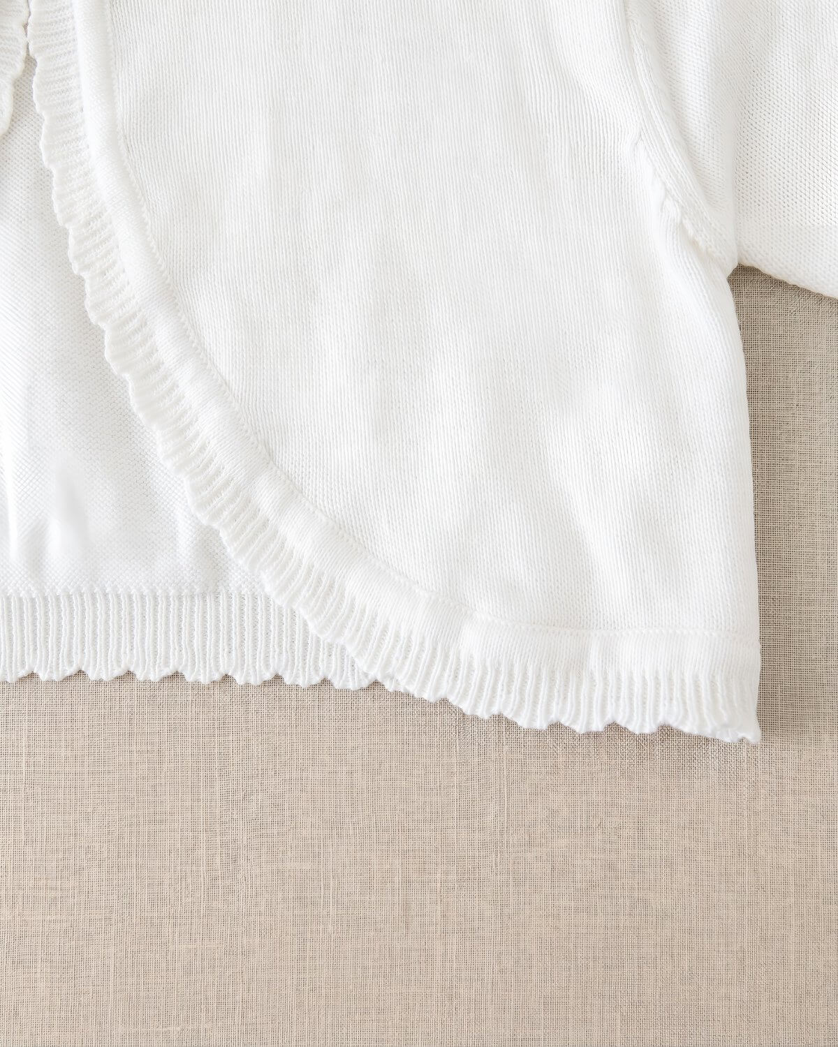 Detailed fabric view of the premium fine-combed cotton knit shrug showcasing the delicate scalloped wavy borders along the hemline.